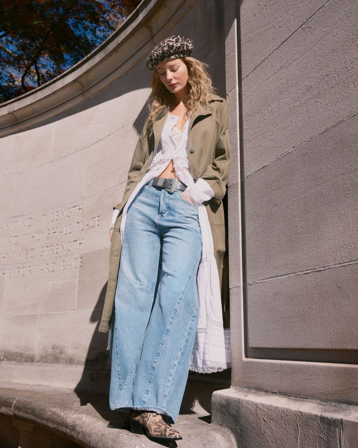 A woman wearing a Free People beret, dress, trench coat and jeans.