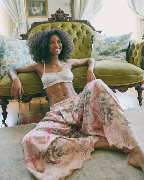 A woman in a bralette and printed pink separate pajama pants. 