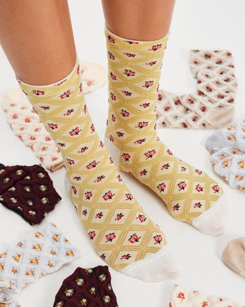 A woman wearing yellow floral printed socks with socks around.
