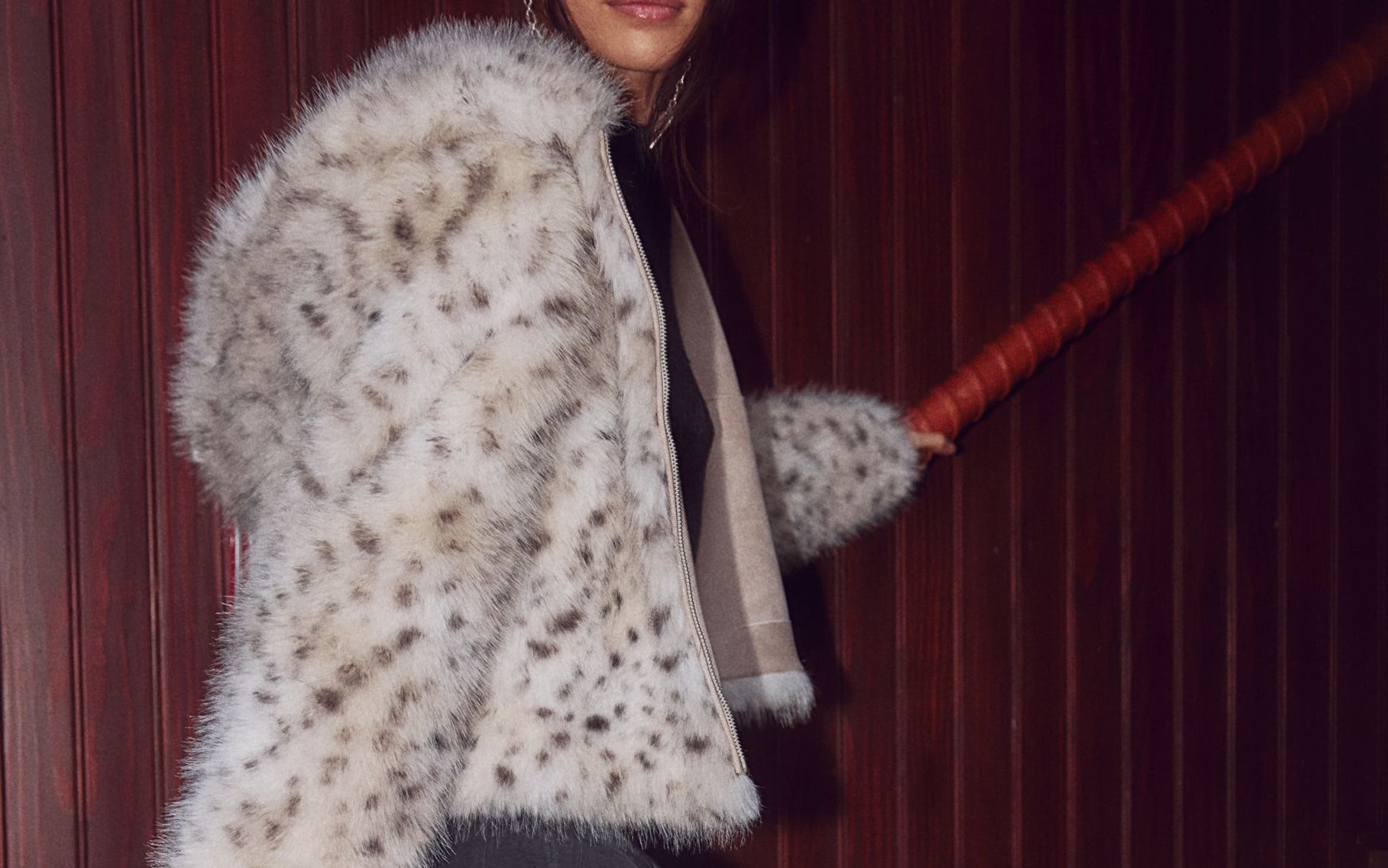 A woman wearing a faux-fur animal print jacket with a skirt.