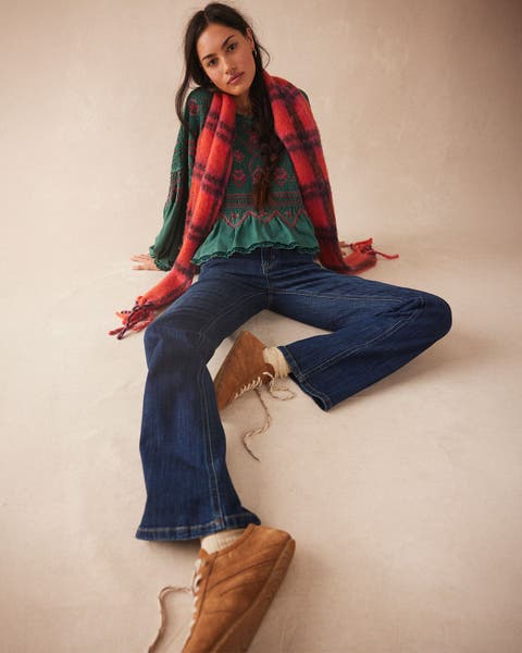 Woman wearing black and red checkered scarf over a green blouse and dark wash jeans