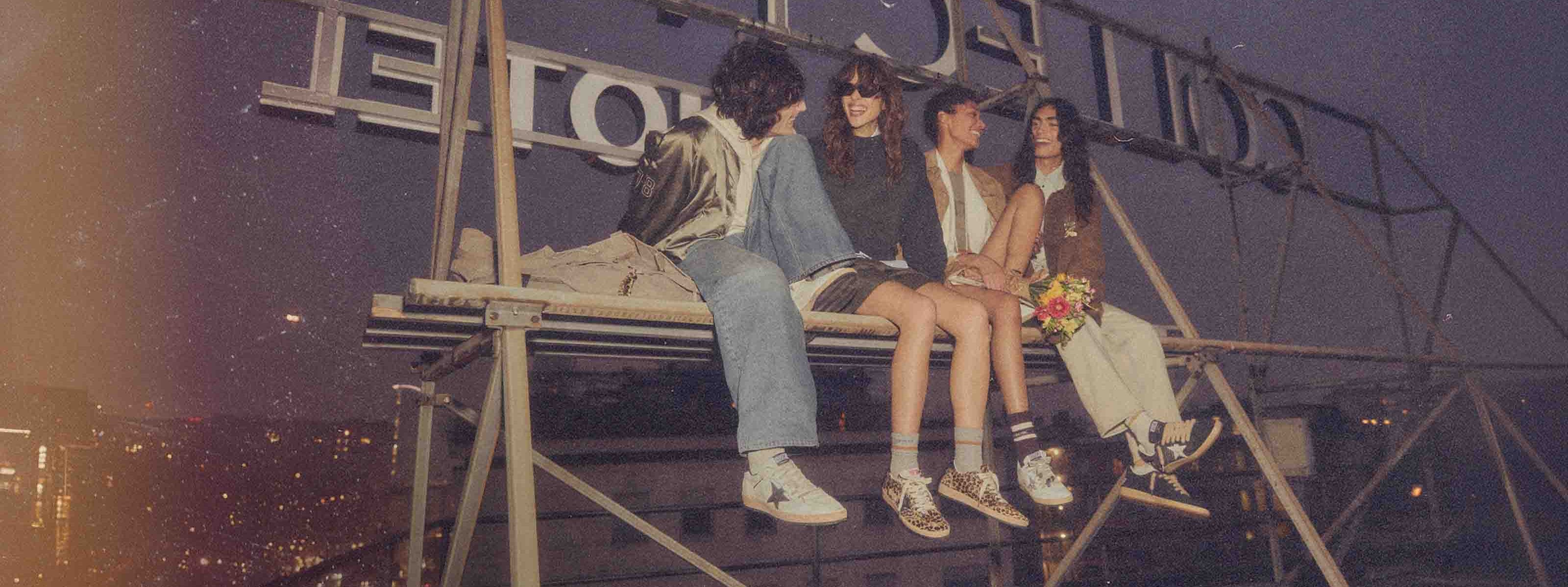 4 people sitting on a rooftop wearing Golden Goose shoes.