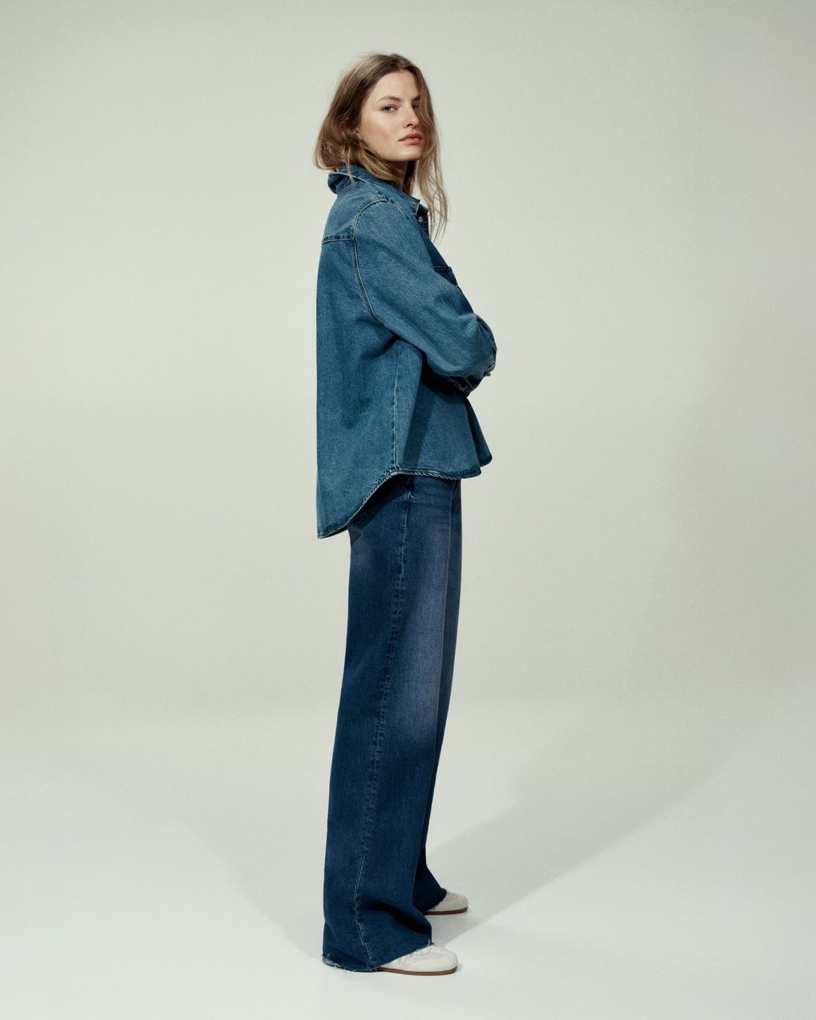 Woman wearing a denim shirt and jeans.