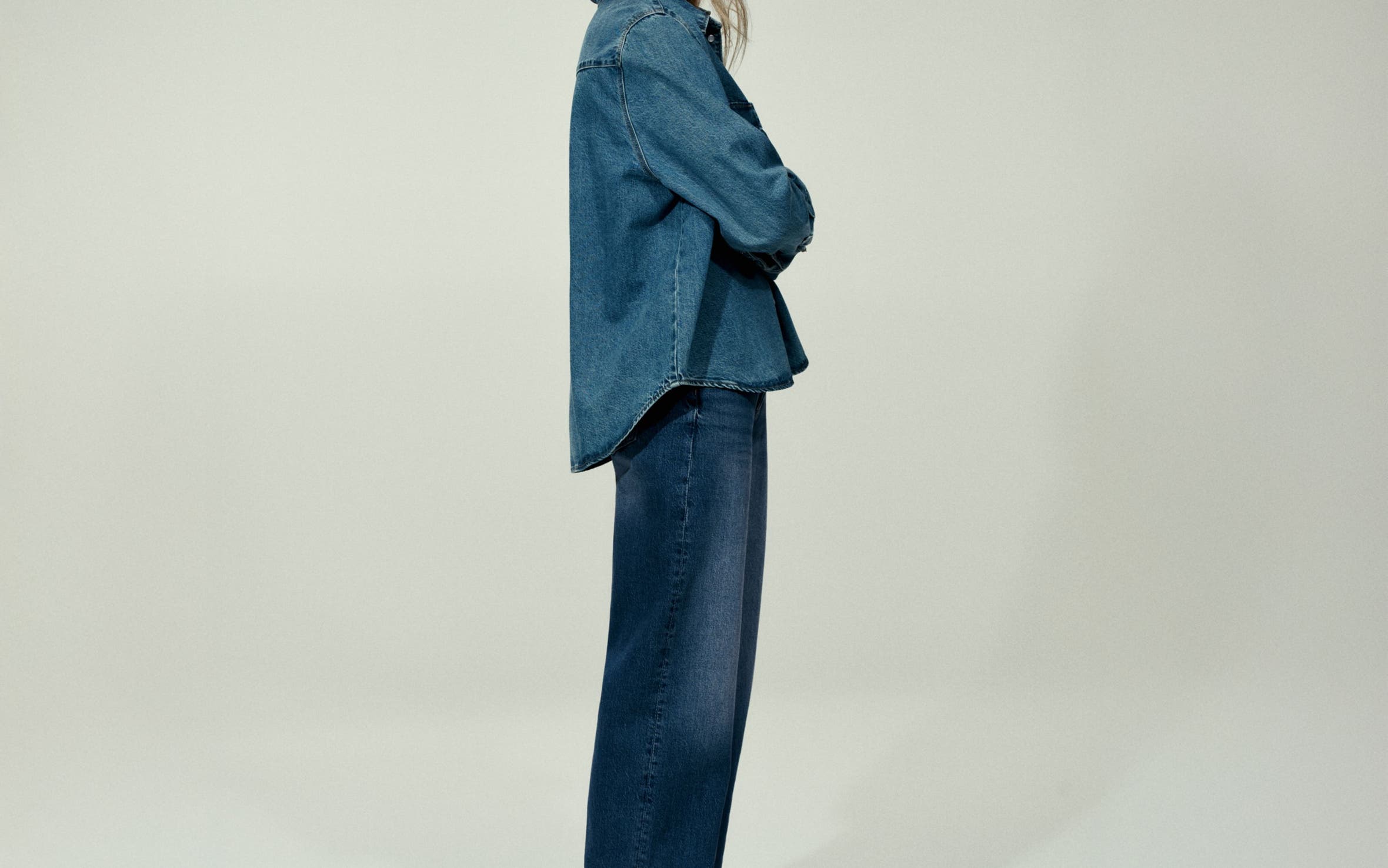 Woman wearing a denim shirt and jeans.