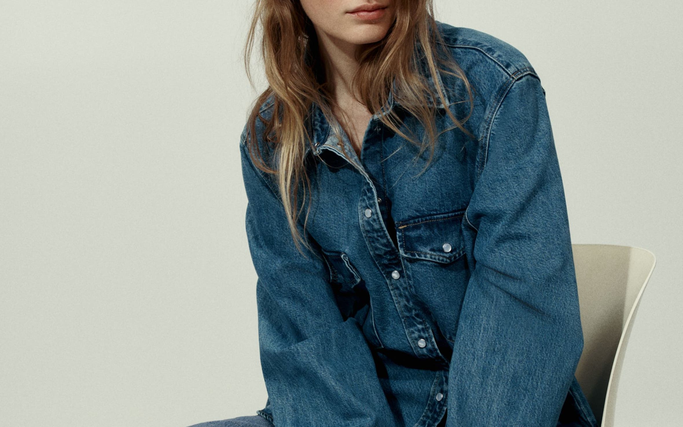 A woman wearing a denim shirt and jeans.