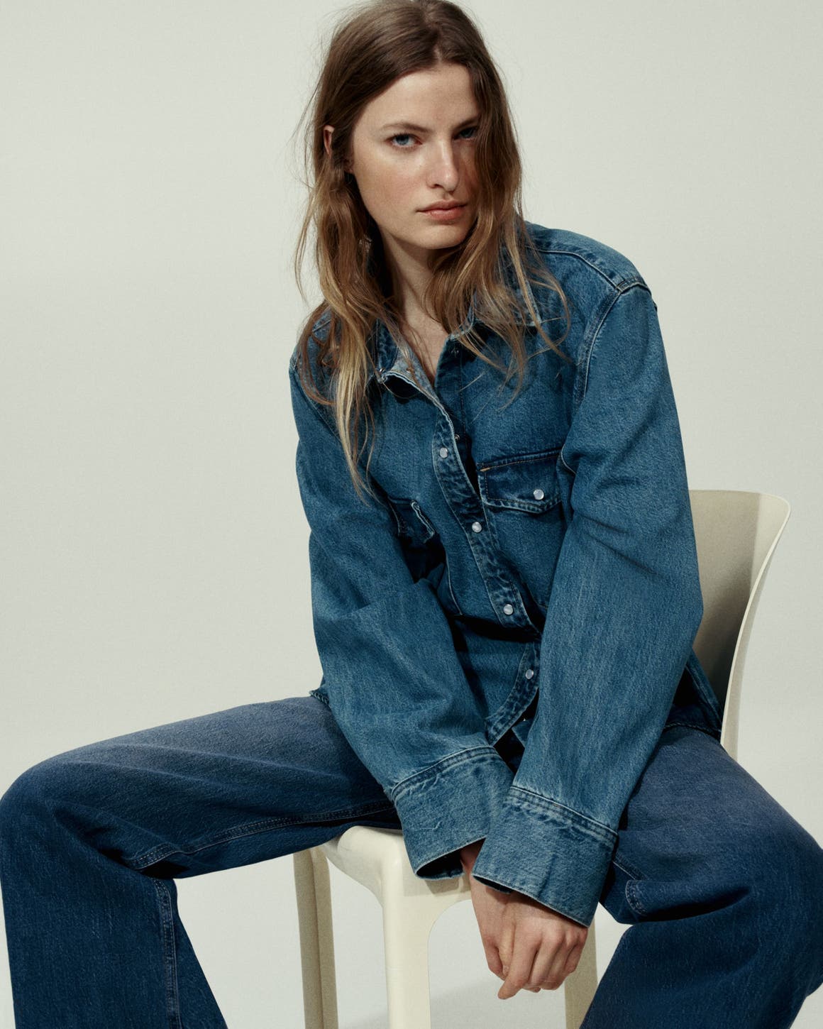 A woman wearing a denim shirt and jeans.