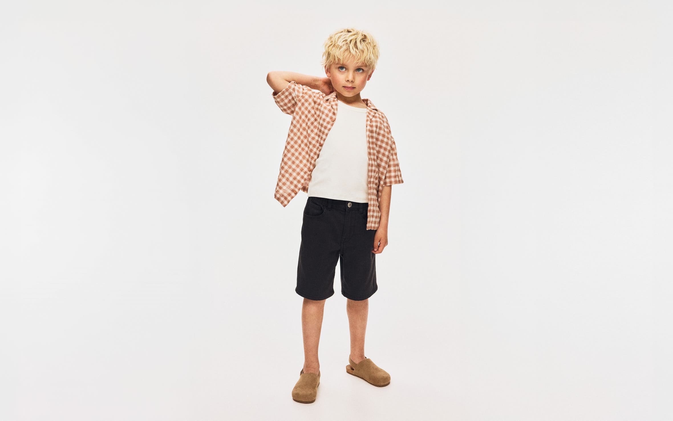 A boy wearing a plaid shirt and shorts from H&M.