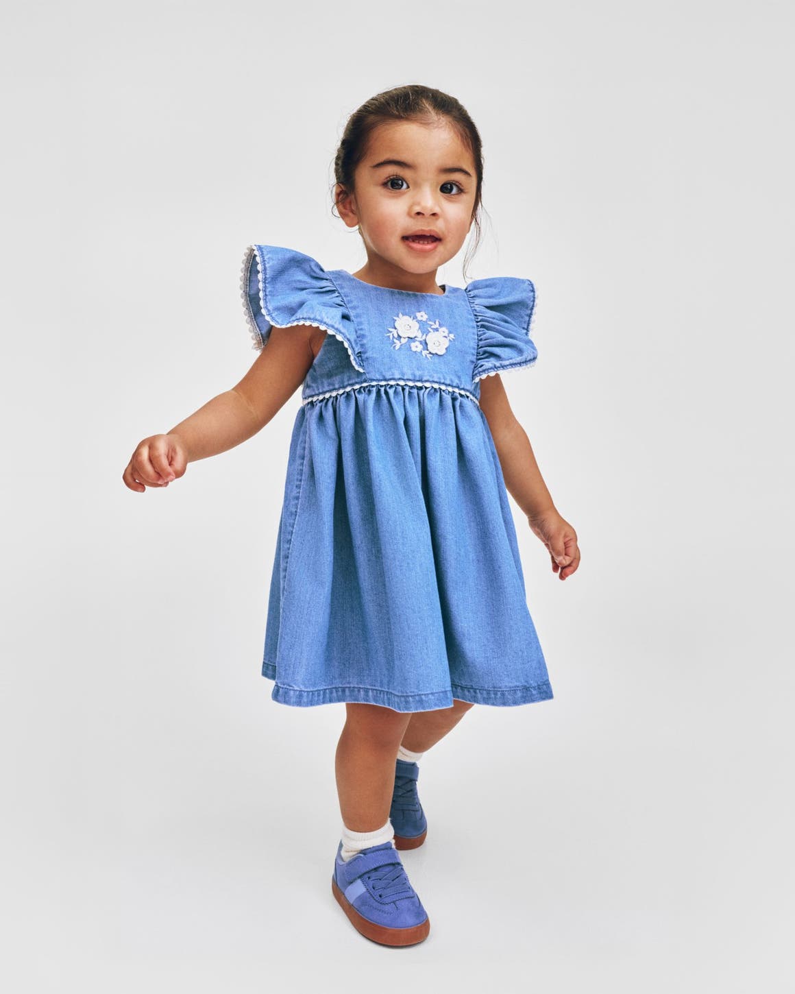 A little girl wearing a denim dress from H&M.