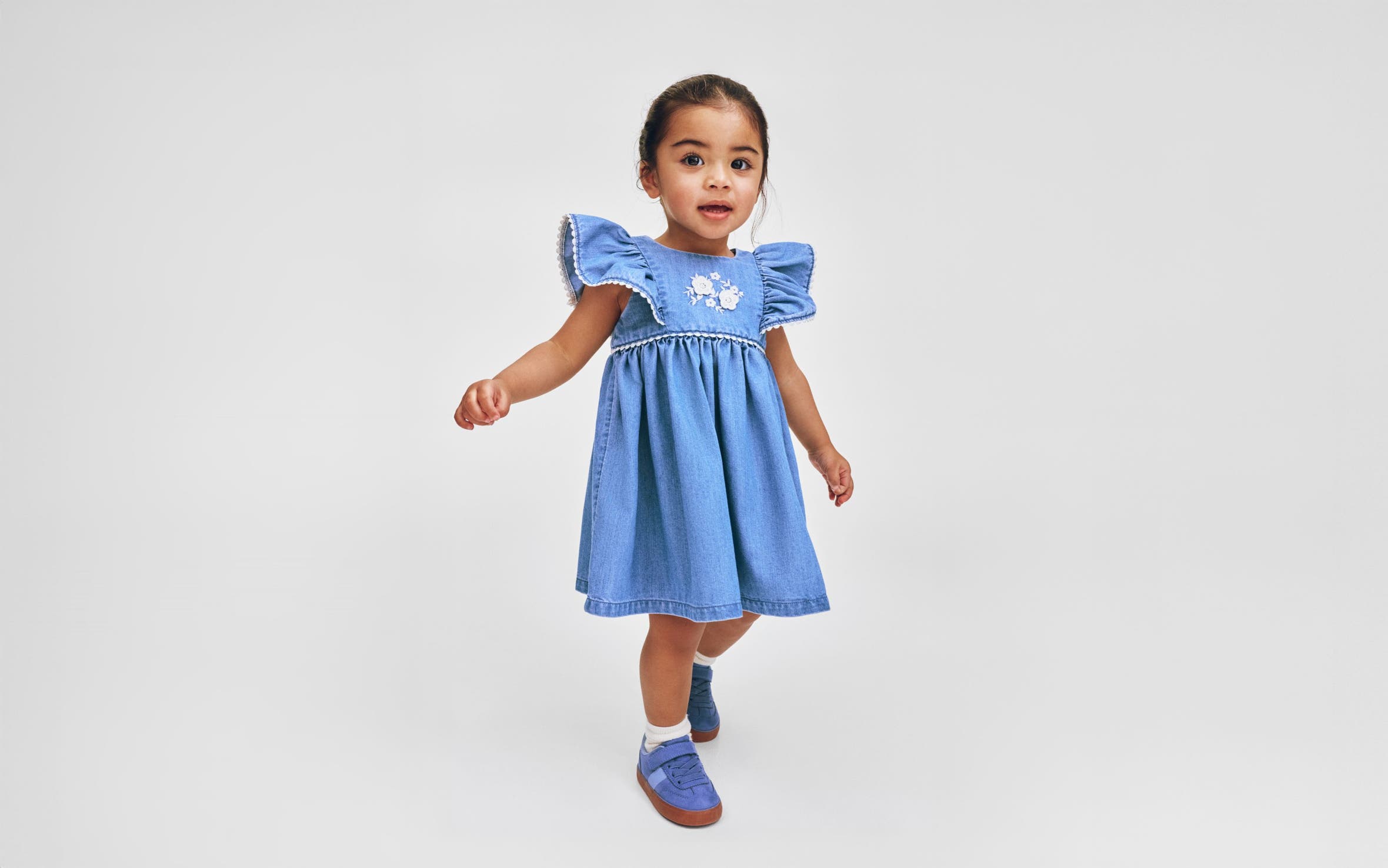 A little girl wearing a denim dress from H&M.