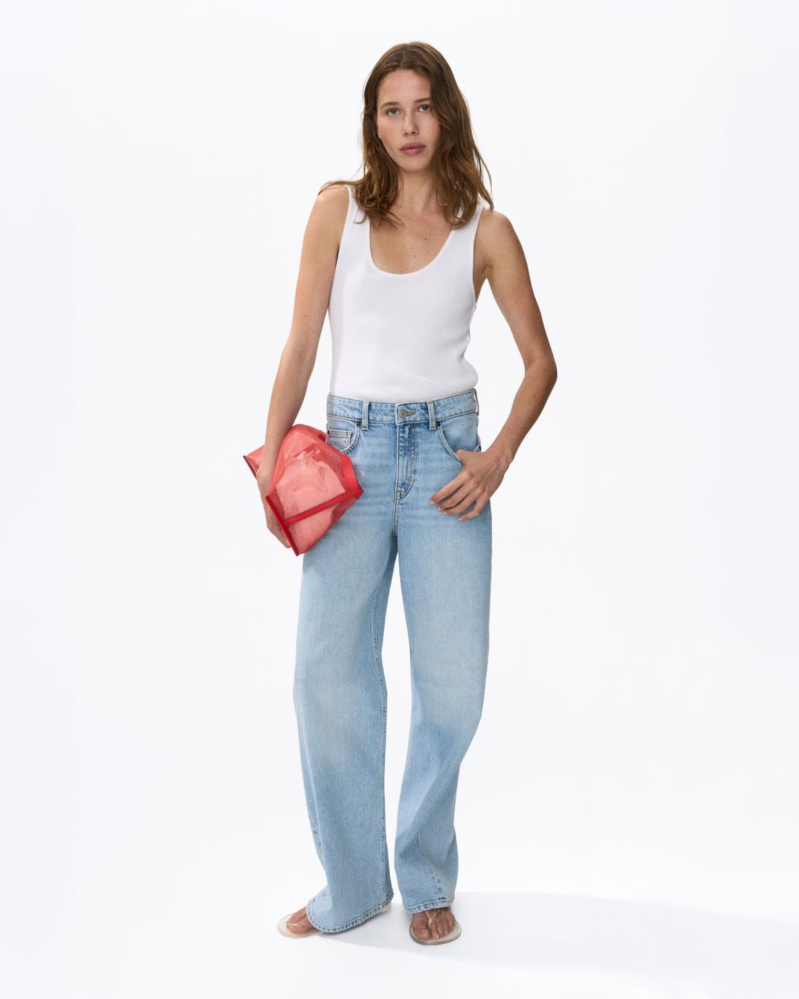 A woman wearing a tank top and boyfriend jeans.