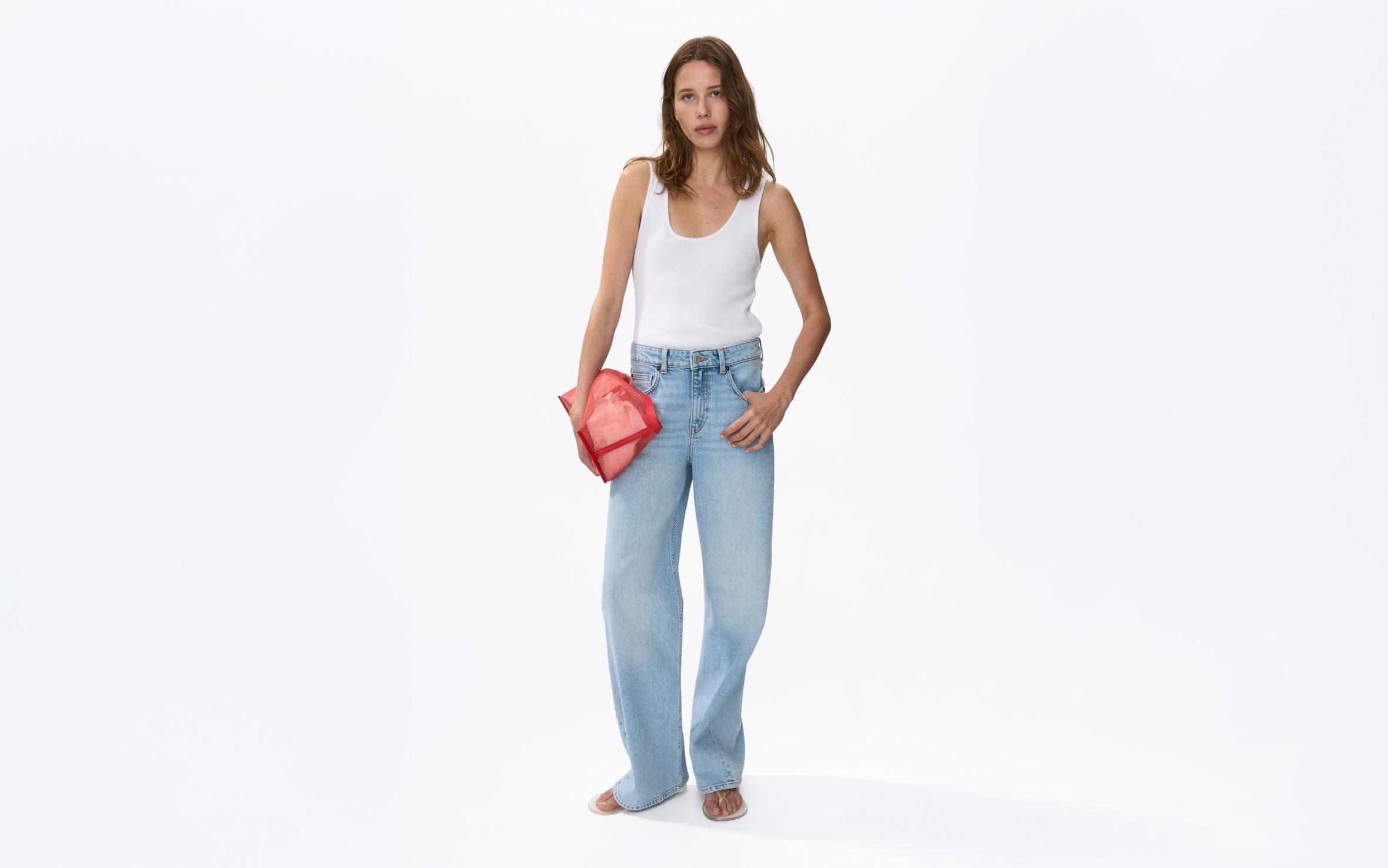 A woman wearing a tank top and boyfriend jeans.