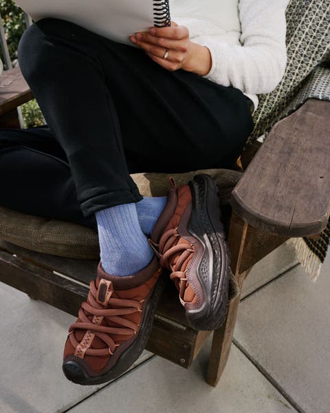 Man wearing Hoka shoes sitting on a chair.