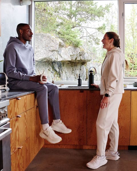 Man and woman wearing Hoka running shoes in a kitchen.