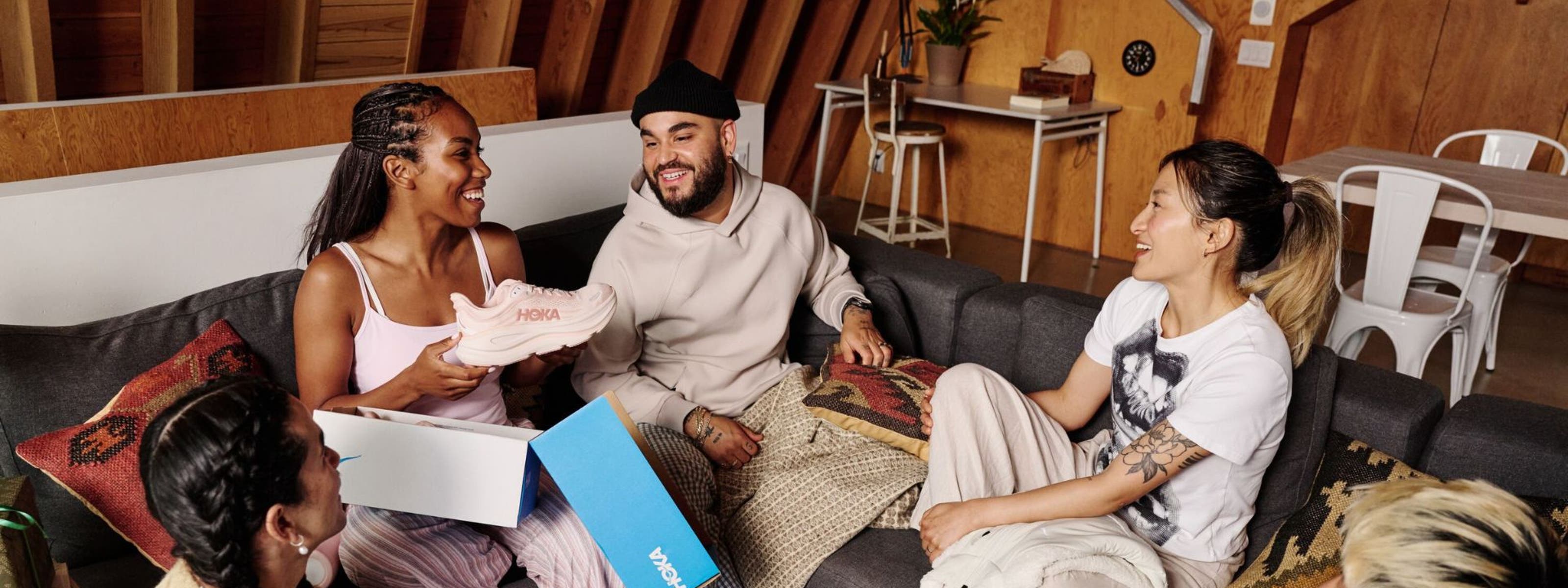 Woman opening a pair of Hoka shoes in front of friends.