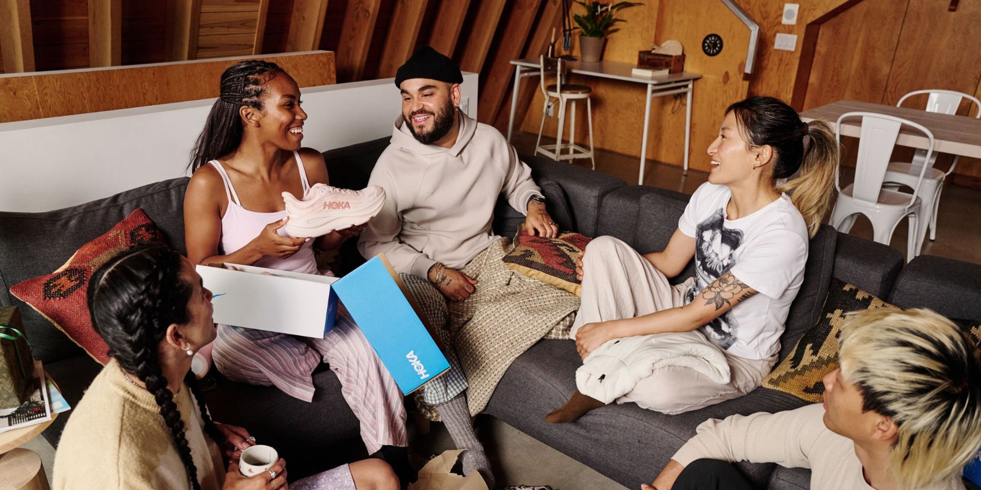 Woman opening a pair of Hoka shoes in front of friends.