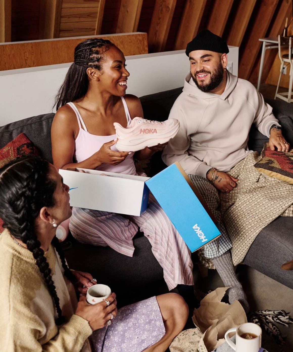 Woman opening a pair of Hoka shoes in front of friends.