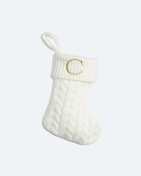Ivory cable-knit Christmas stocking with a gold monogram "C" on the cuff.