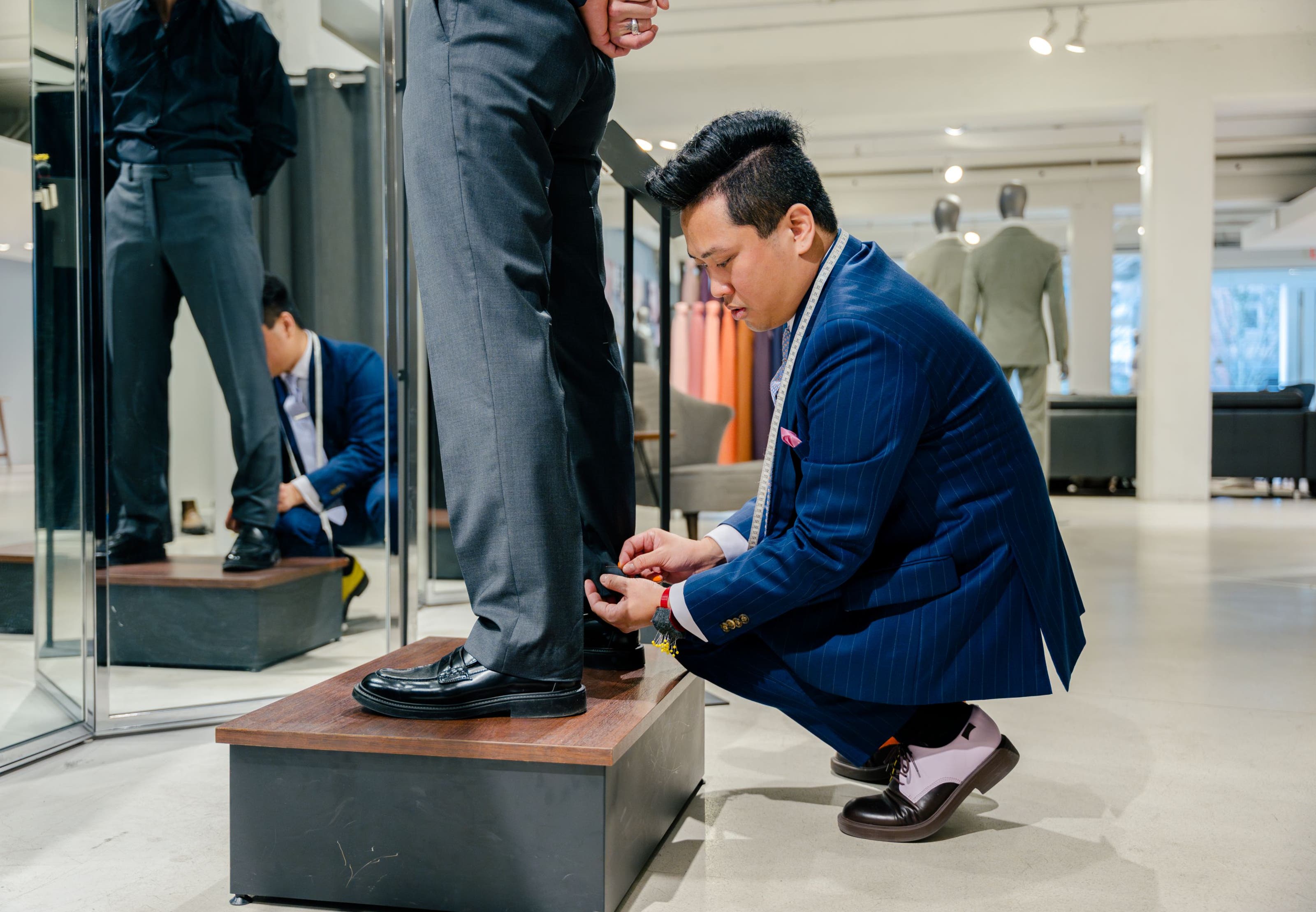 A tailor making adjustments to a customer's pants.