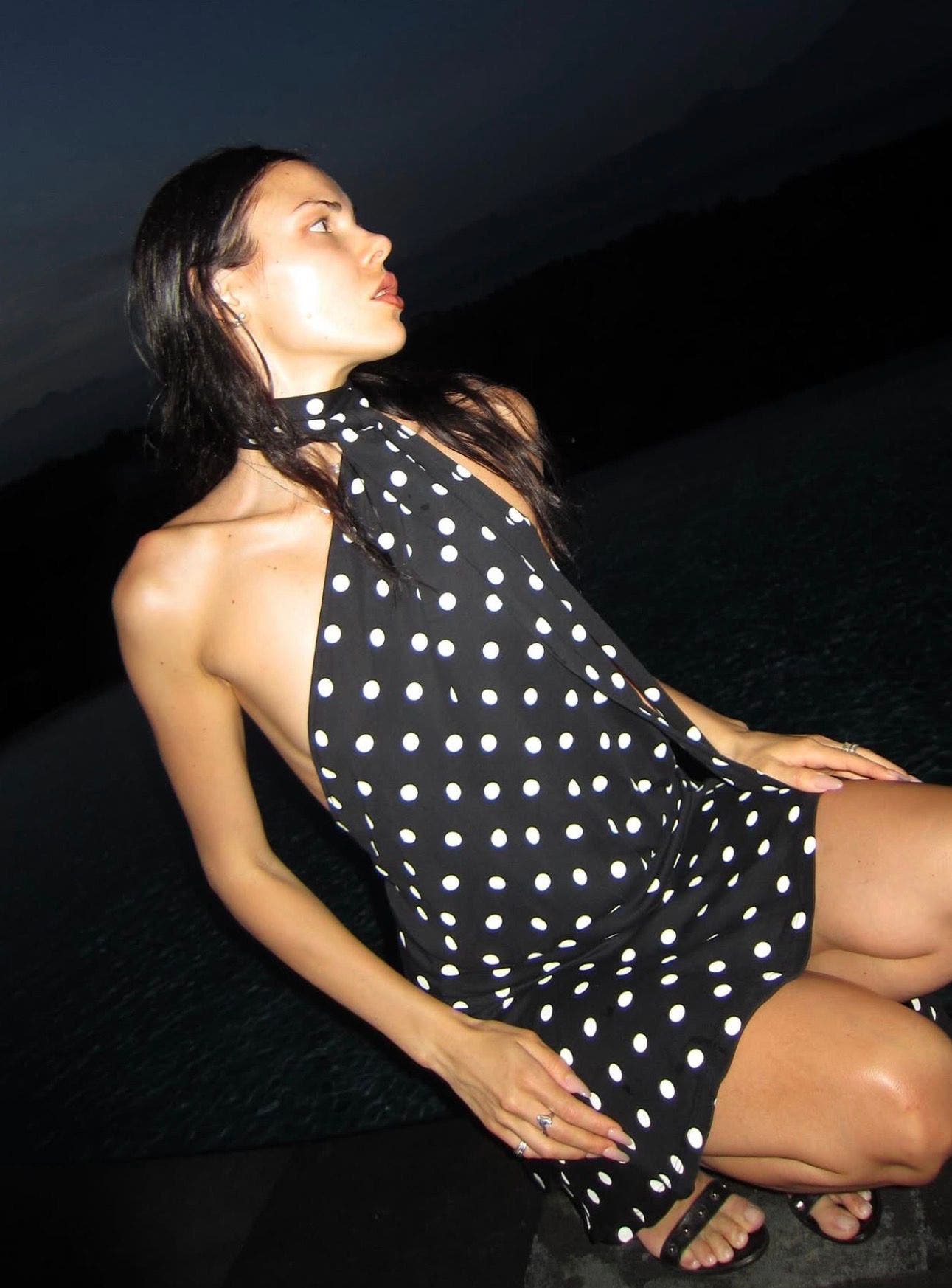 A woman wearing a black-and-white polka dot halter minidress.