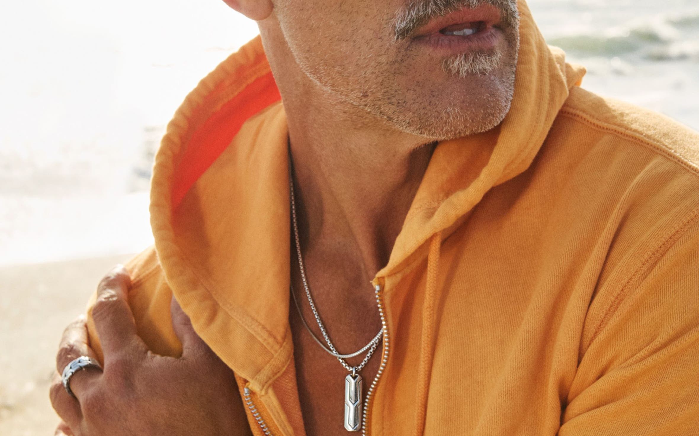 A man at the beach wearing layered John Hardy necklaces and bracelets.