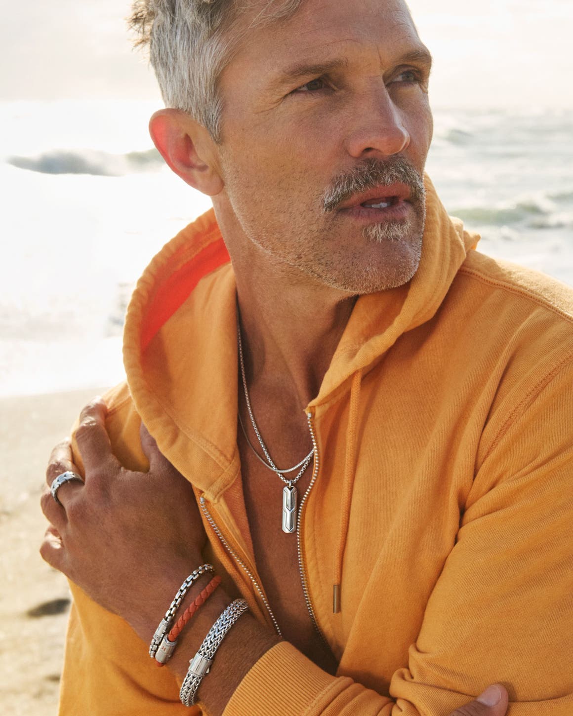 A man at the beach wearing layered John Hardy necklaces and bracelets.