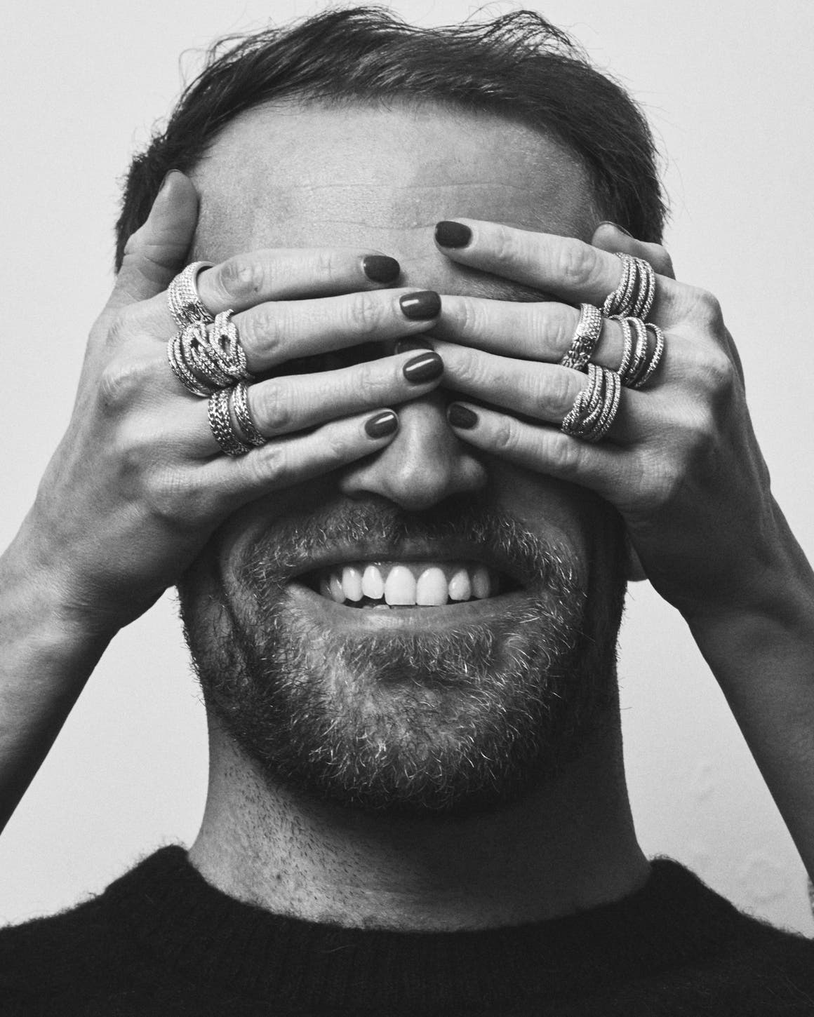 A man whose eyes are covered by a woman's hands.