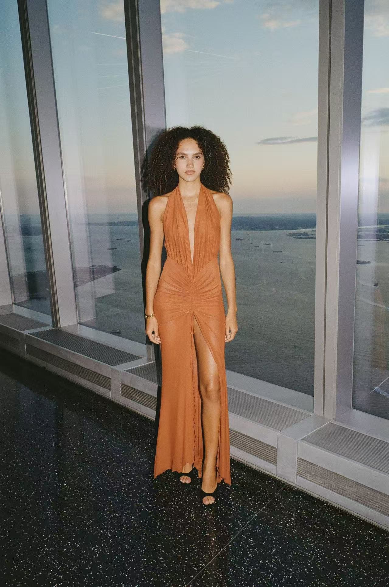 Woman wearing an orange gown from Kim Shu with black heels.