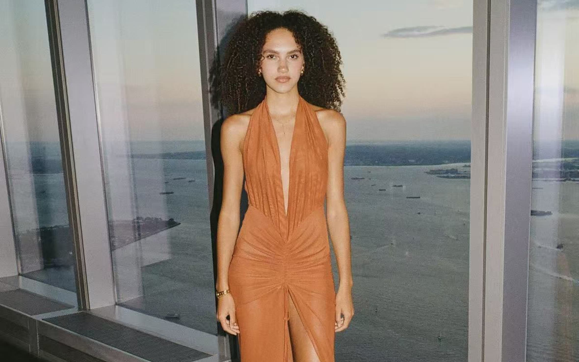 Woman wearing an orange gown from Kim Shu with black heels.