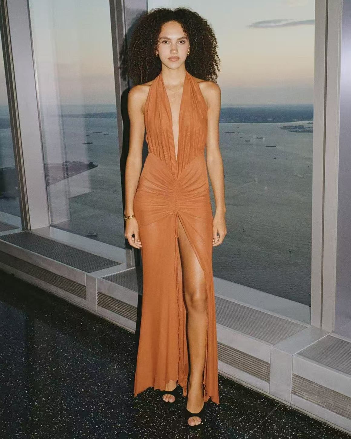 Woman wearing an orange gown from Kim Shu with black heels.