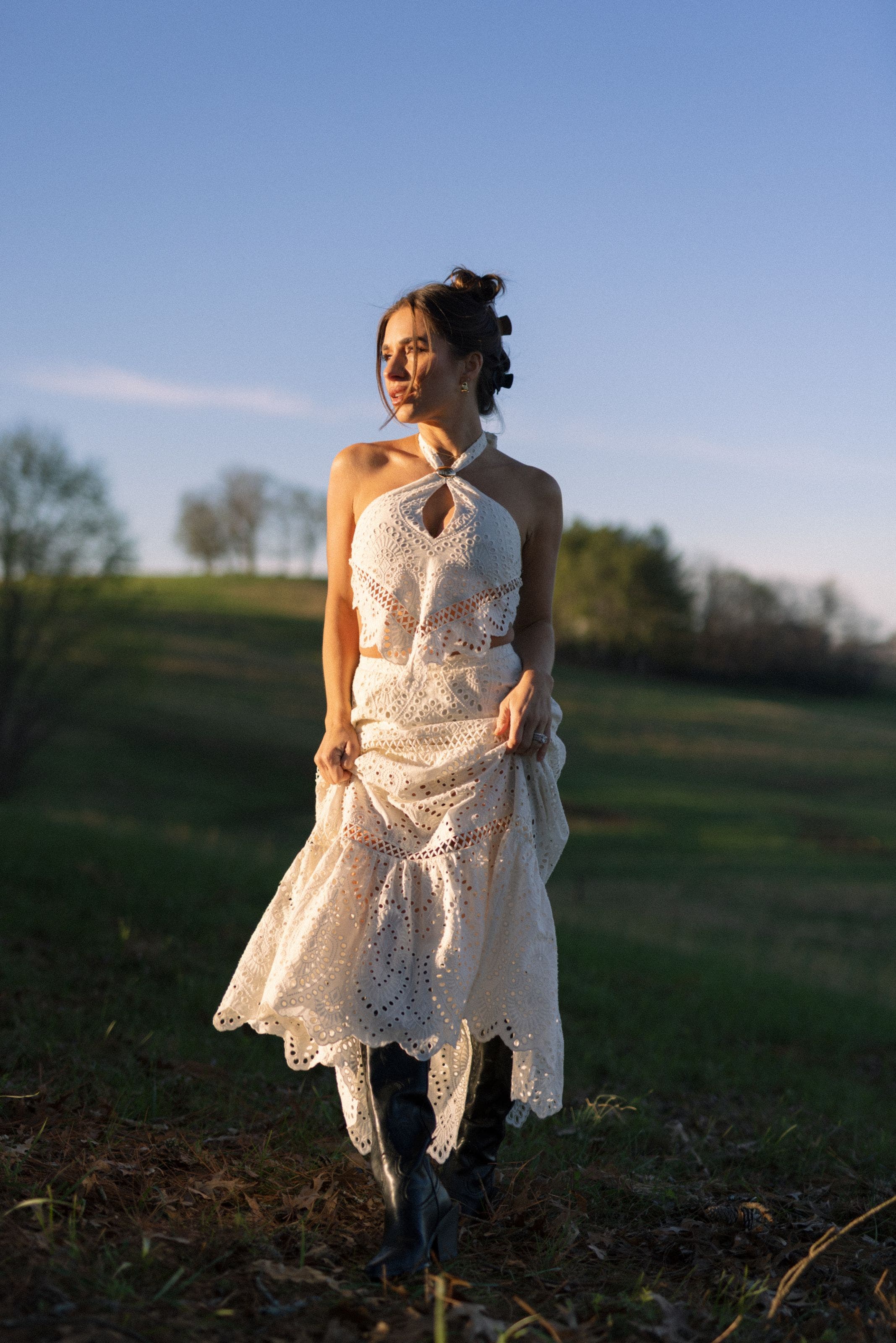 A woman wearing a matching white eyelet top and maxi skirt.