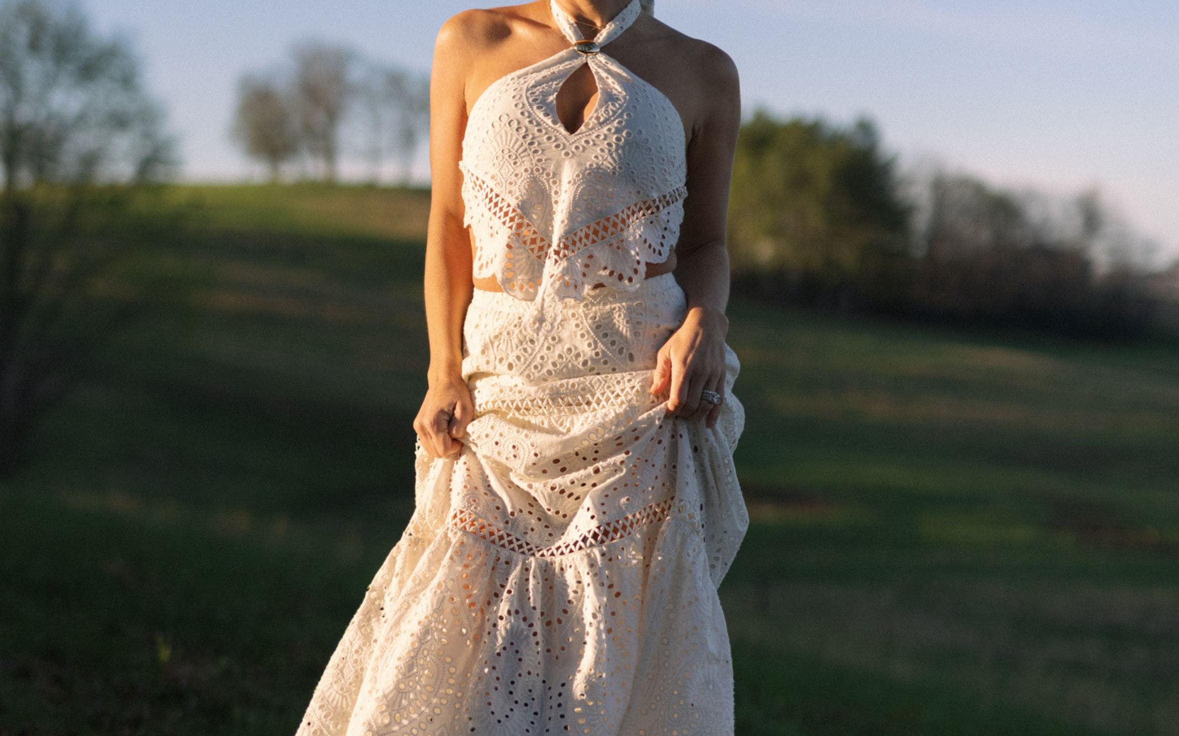 A woman wearing a matching white eyelet top and maxi skirt.