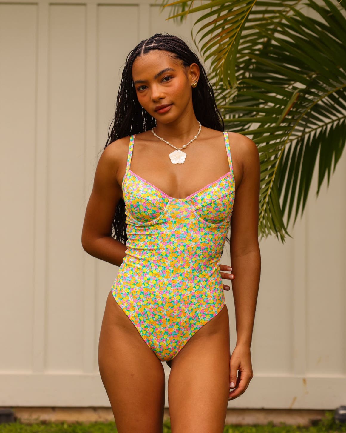 A woman wearing a bright floral-print one-piece swimsuit. 