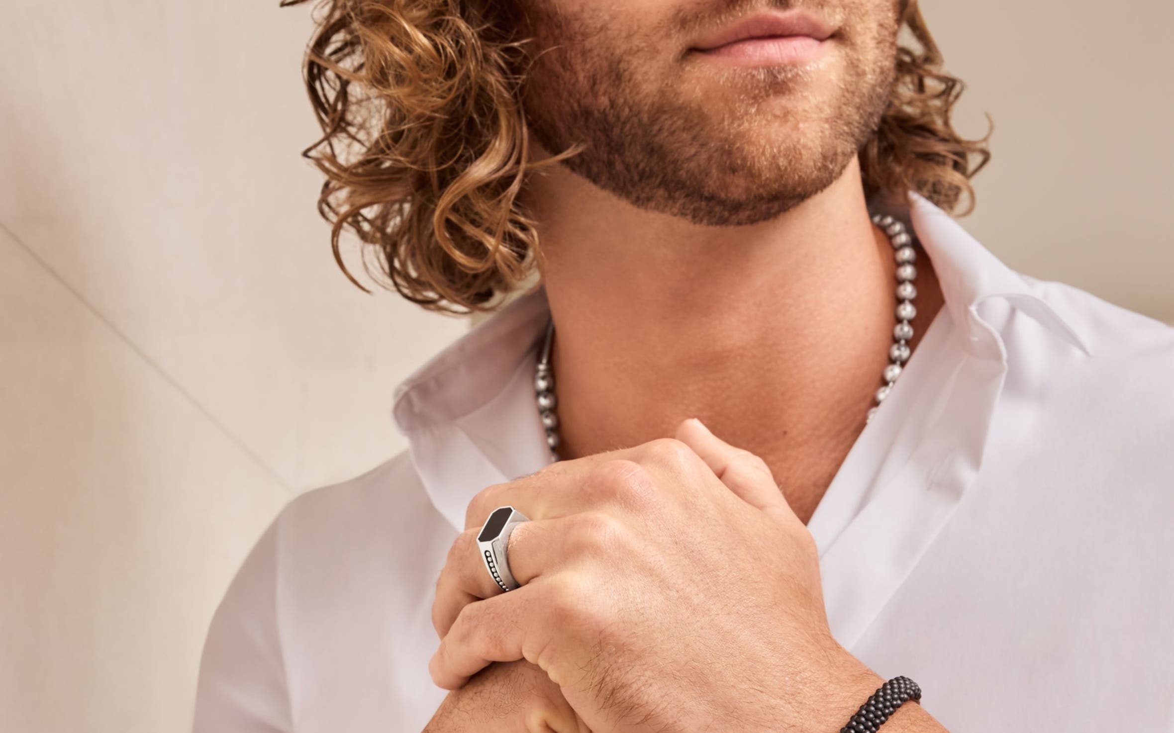 A man wearing a necklace, ring and bracelets.