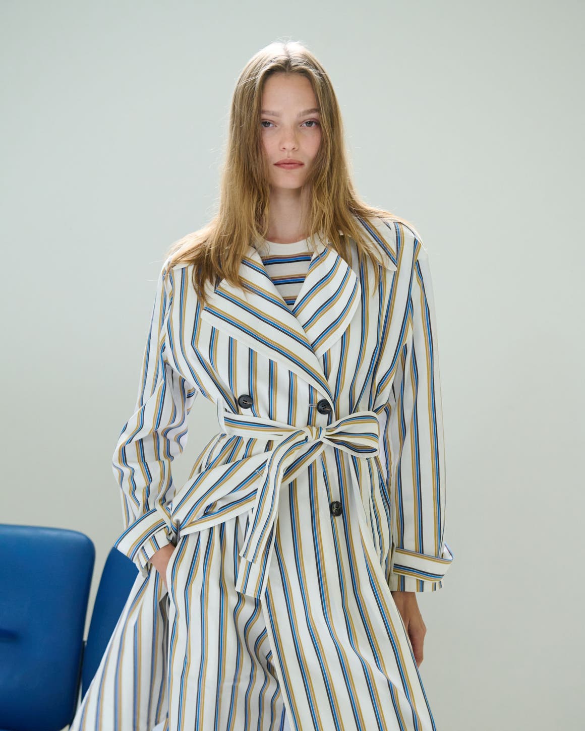 A woman wearing a striped trenchcoat and matching pants over a striped top.