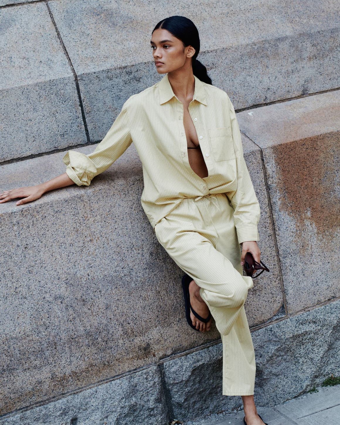 A woman wearing a matching butter yellow shirt and pants set.