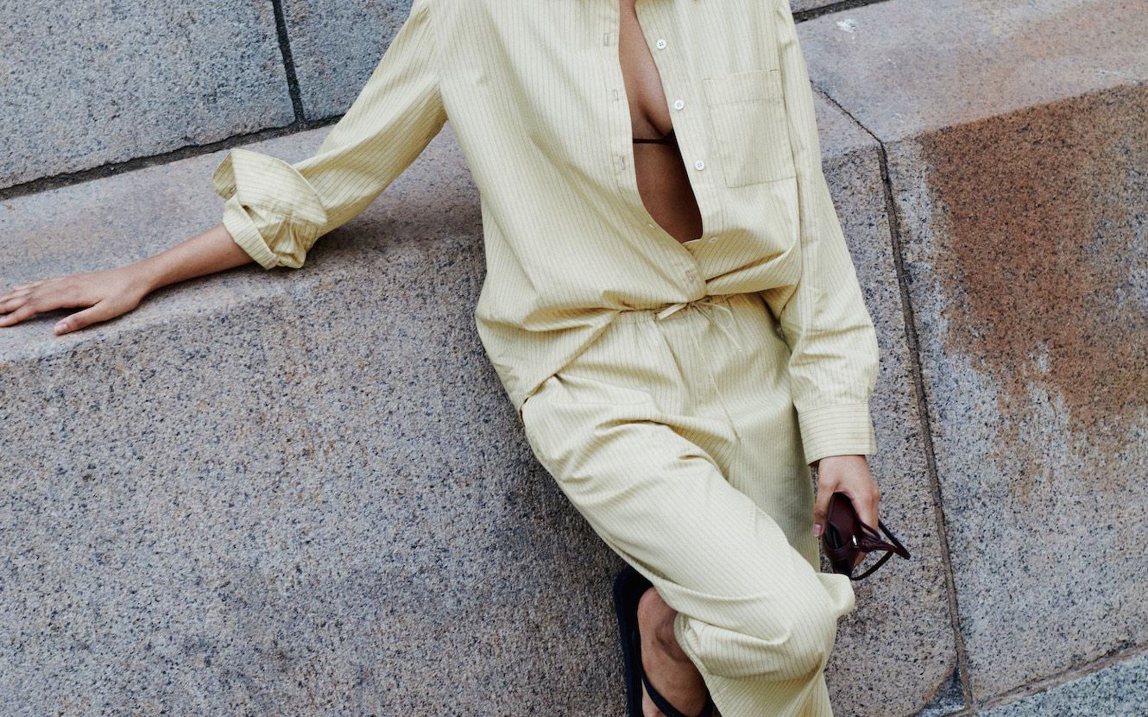 A woman wearing a matching butter yellow shirt and pants set.