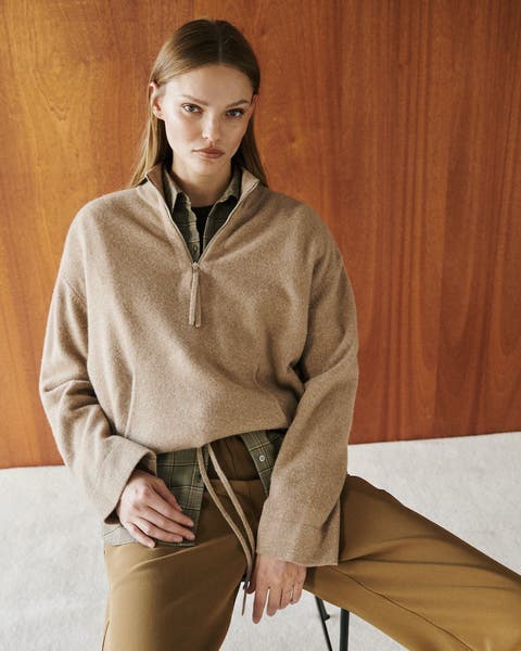 A woman wearing a half zip sweater over a button up shirt.