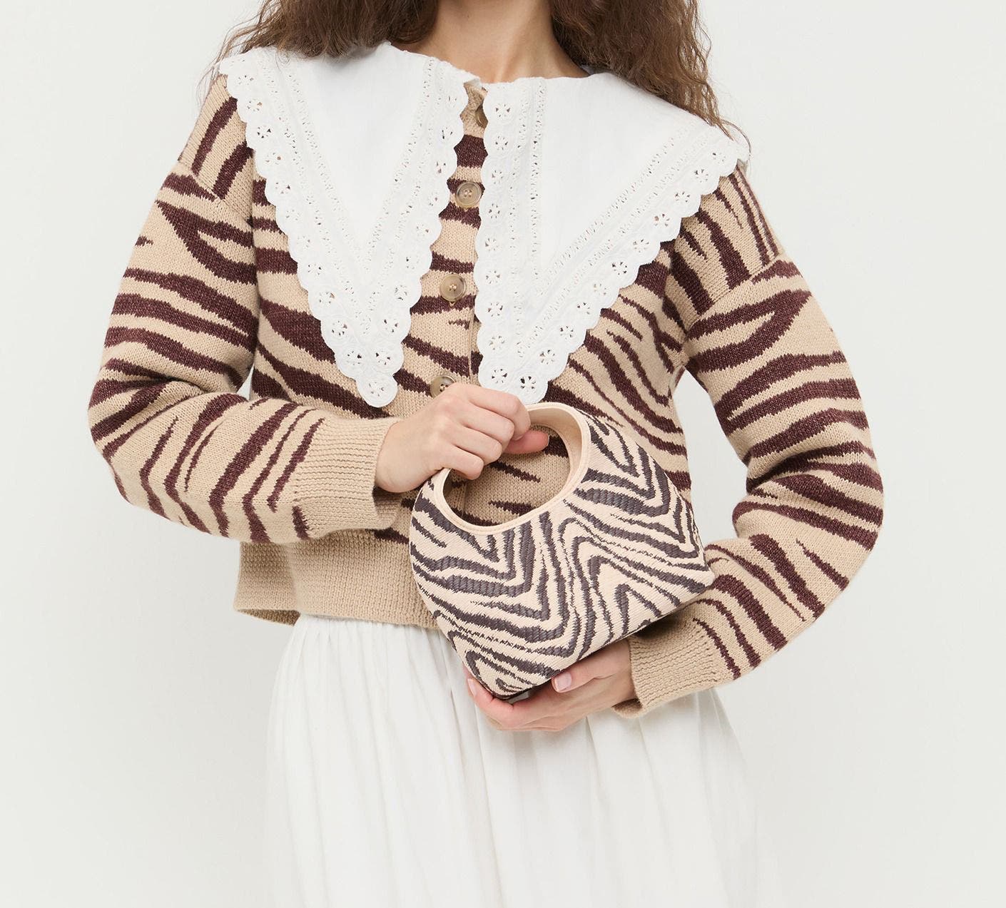 A woman wearing a zebra striped sweater and carrying a zebra print bag. 