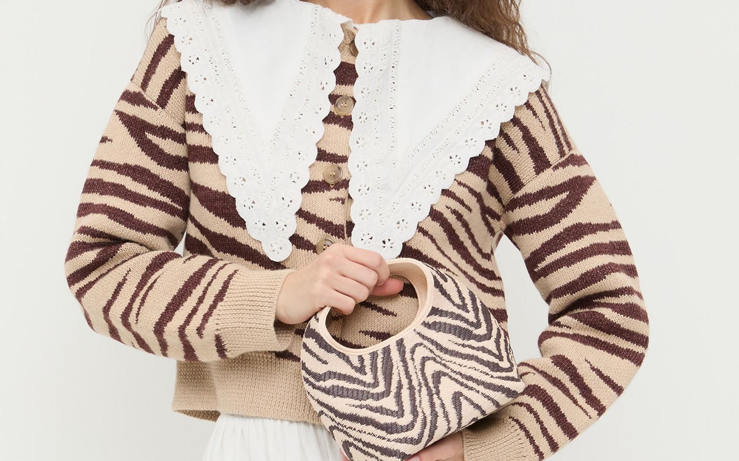 A woman wearing a zebra striped sweater and carrying a zebra print bag.