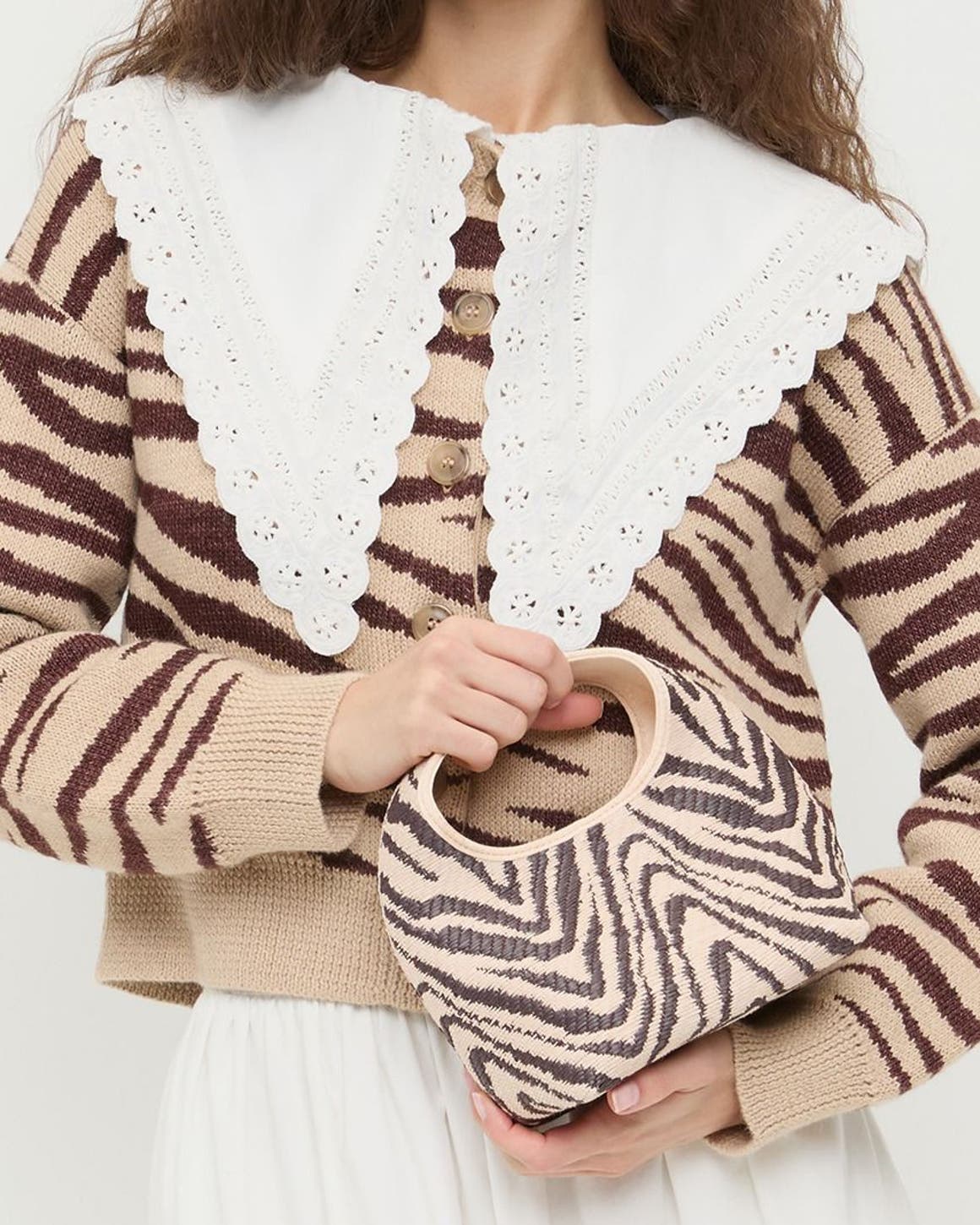 A woman wearing a zebra striped sweater and carrying a zebra print bag.