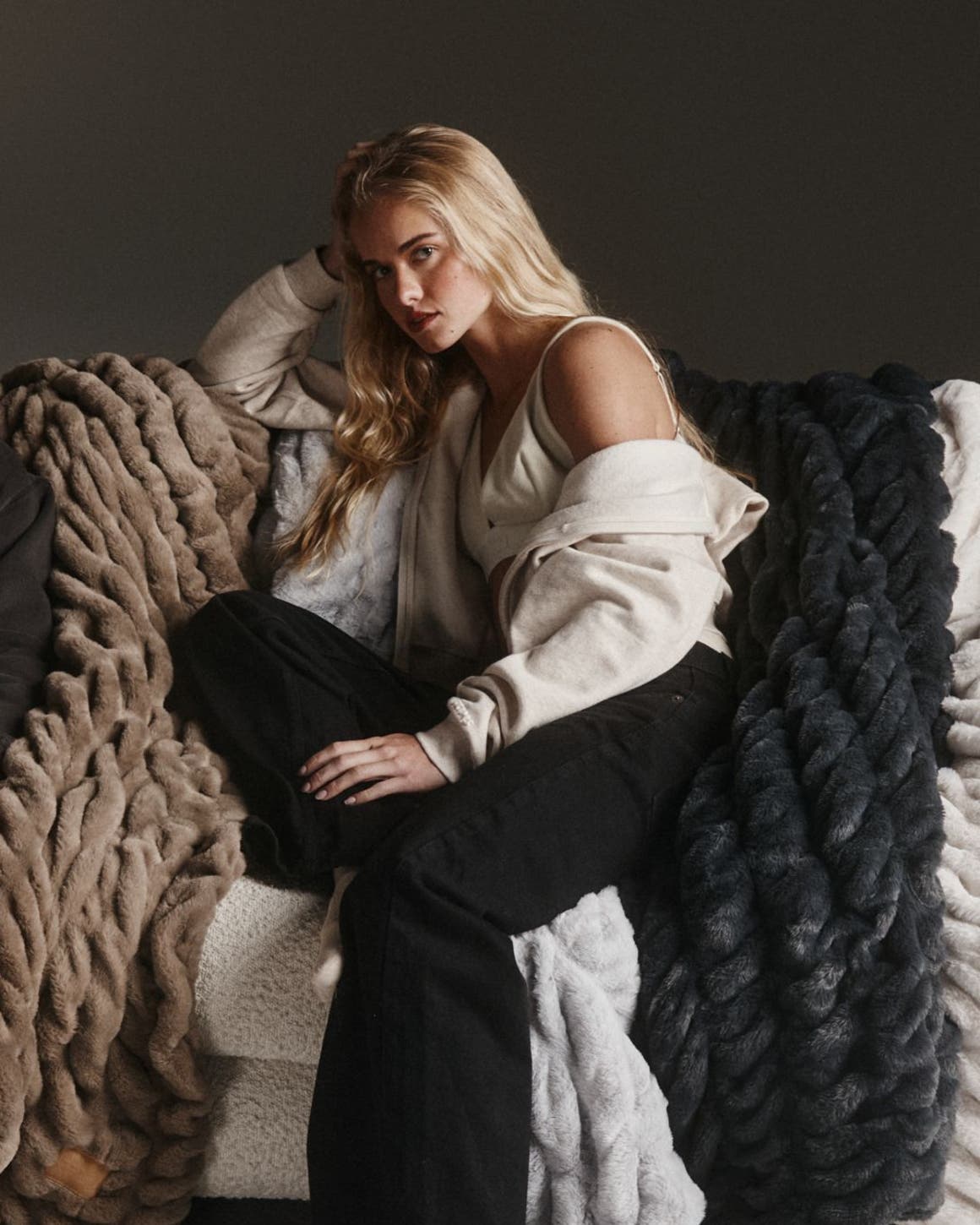 A man and a woman relaxing on chunky knit blankets.
