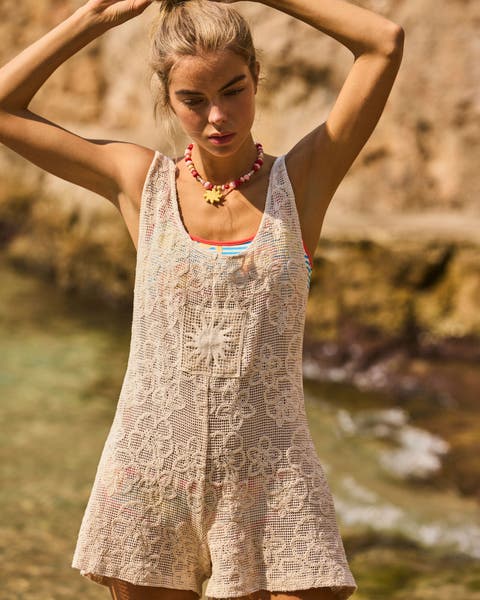 A woman wearing a bathing suit with a crochet cover up.