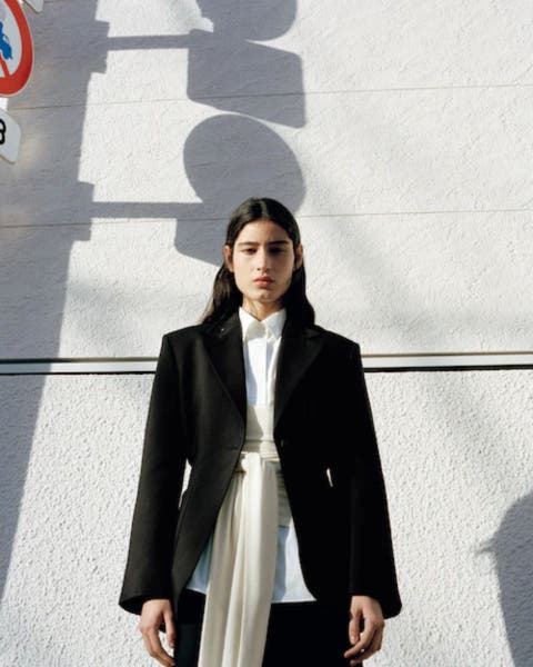 Woman wearing black blazer over a white blouse.