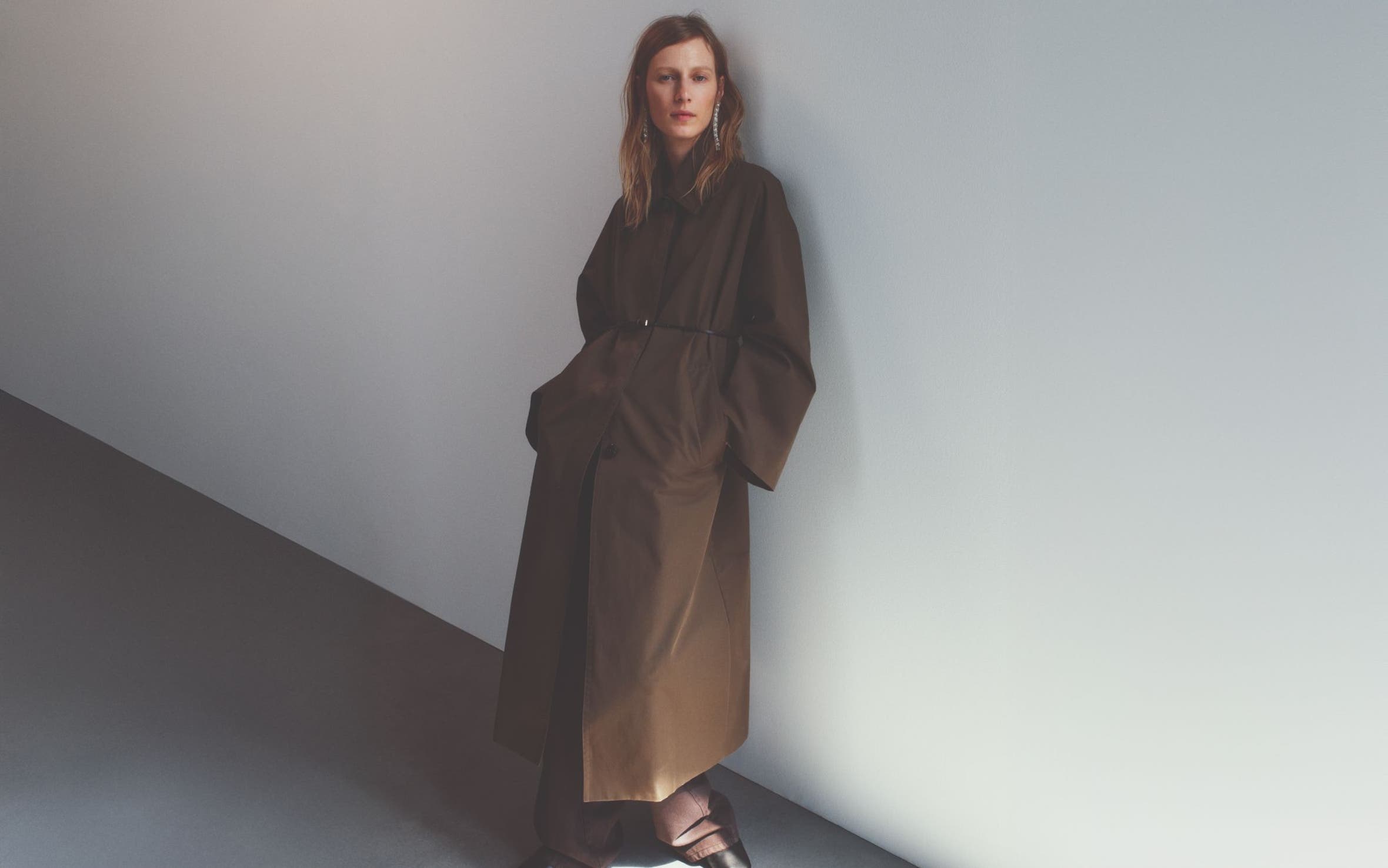 A woman wearing a long brown trenchcoat.