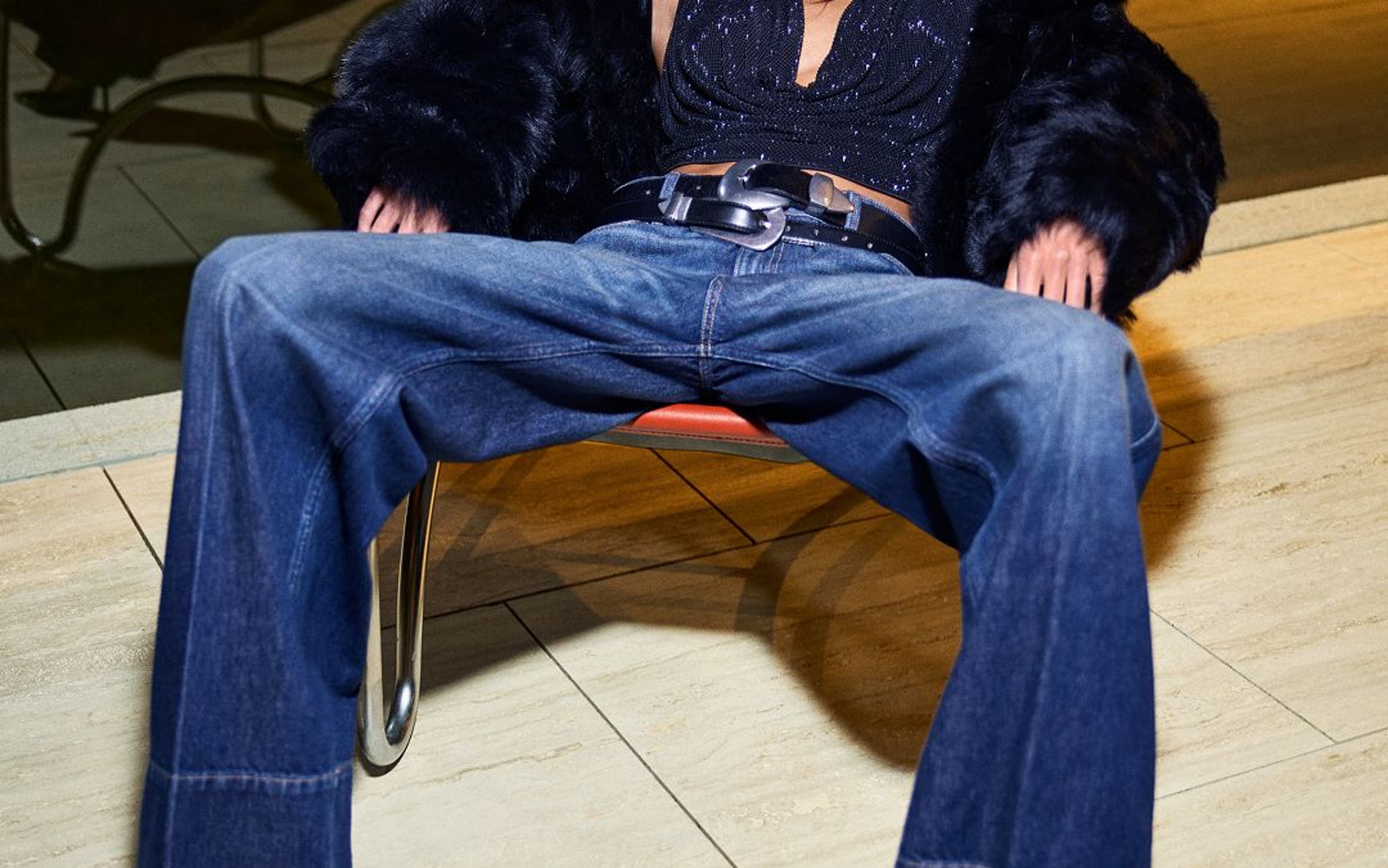 Kaia Gerber wearing a sparkly top, faux-fur coat, jeans, belt and heels.