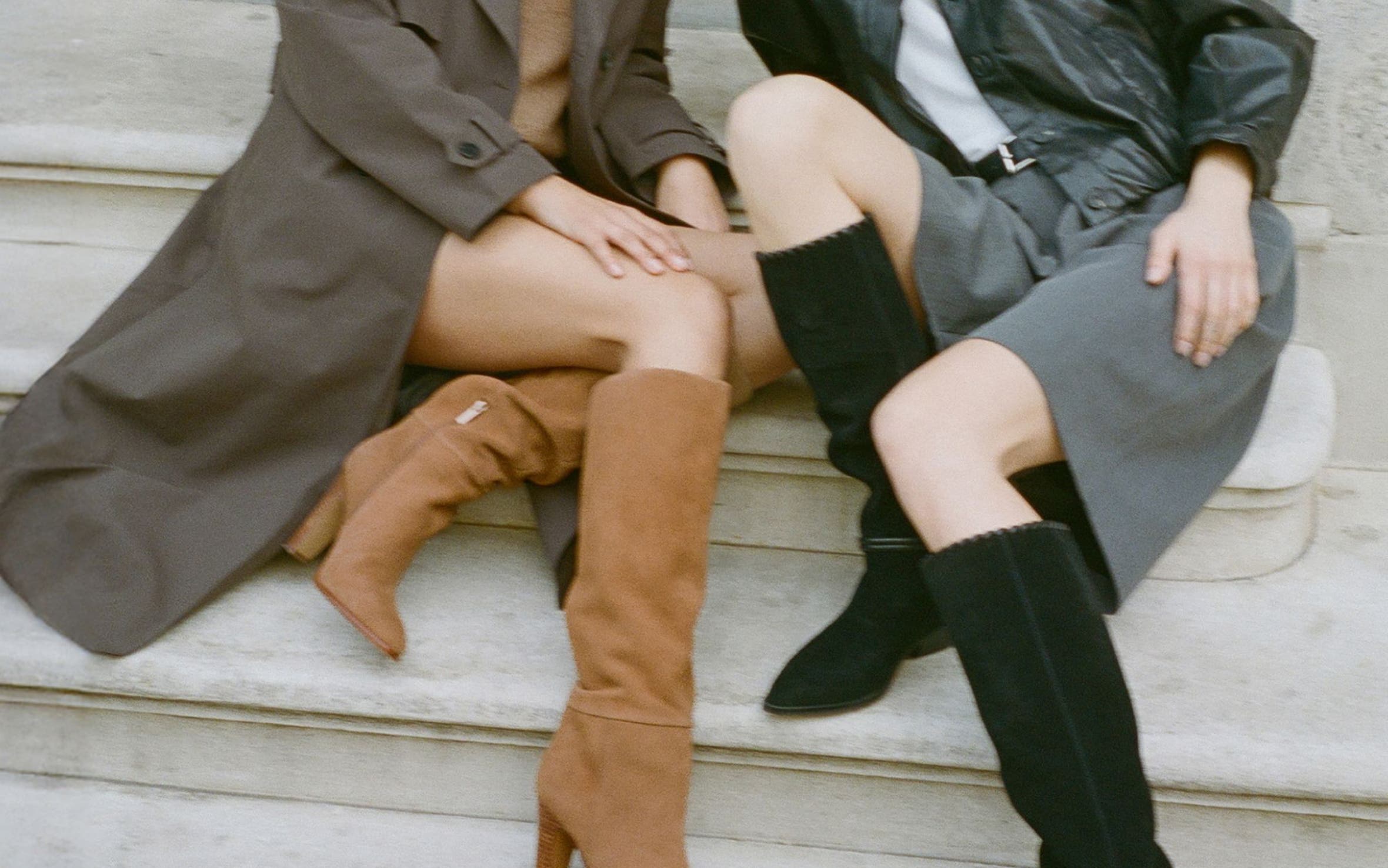 Two girls sitting on the stairs in brown and black suede knee high boots