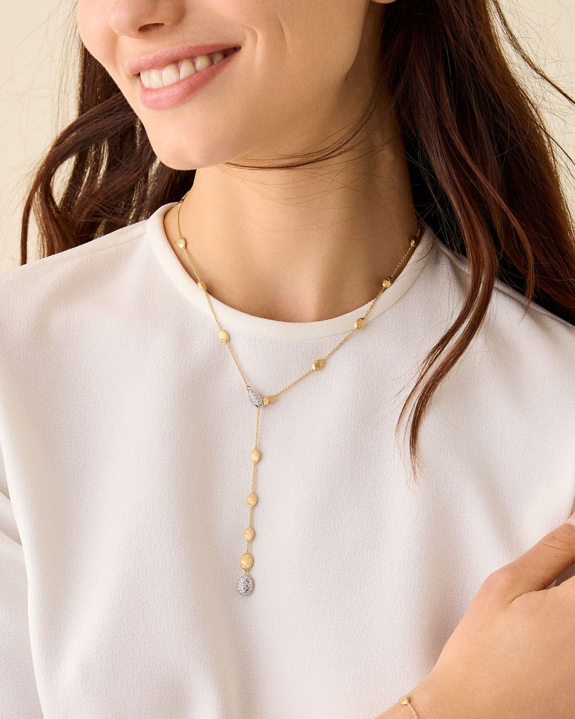 A woman wearing a gold and diamond Marco Bicego necklace.
