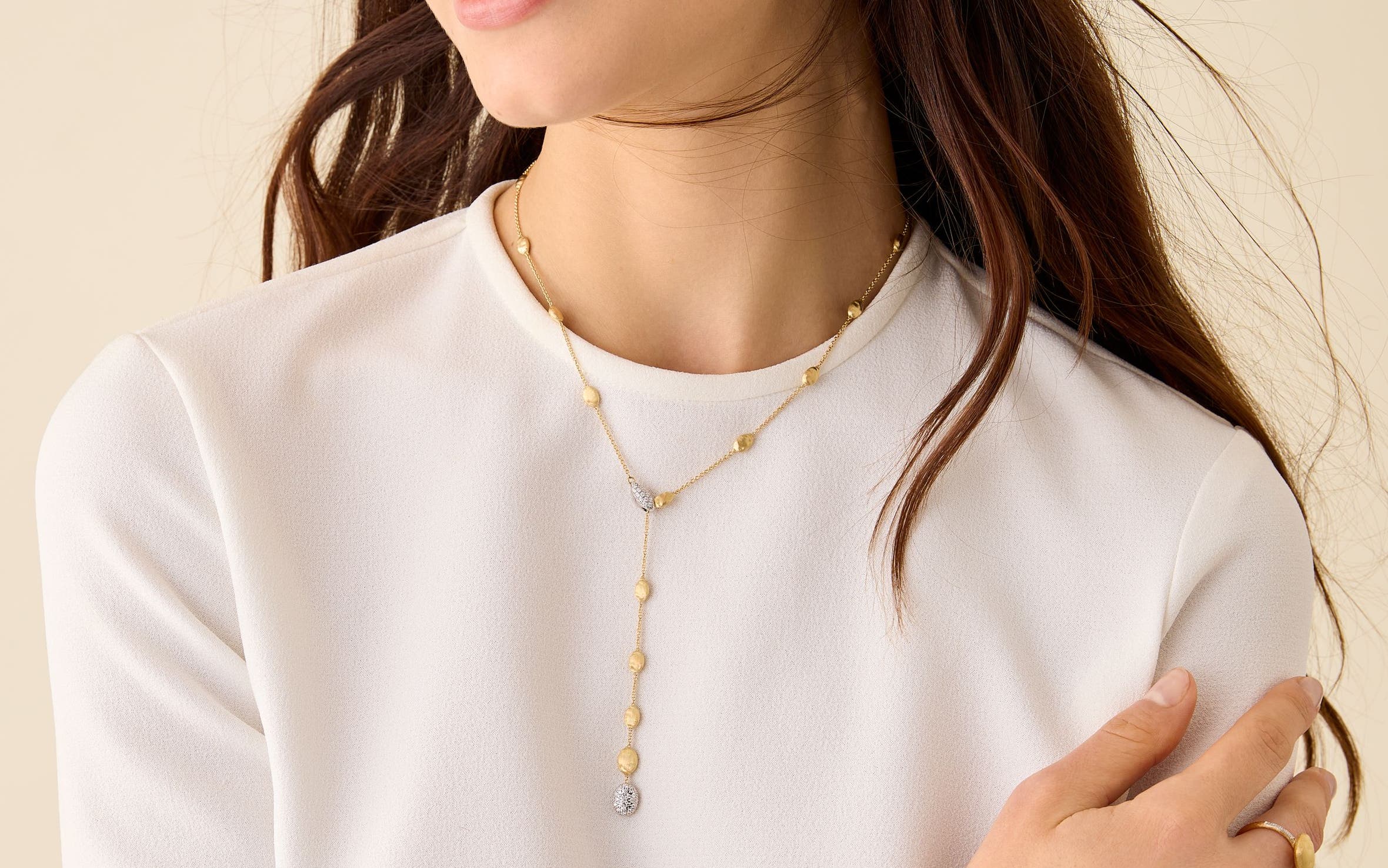 A woman wearing a gold and diamond Marco Bicego necklace.