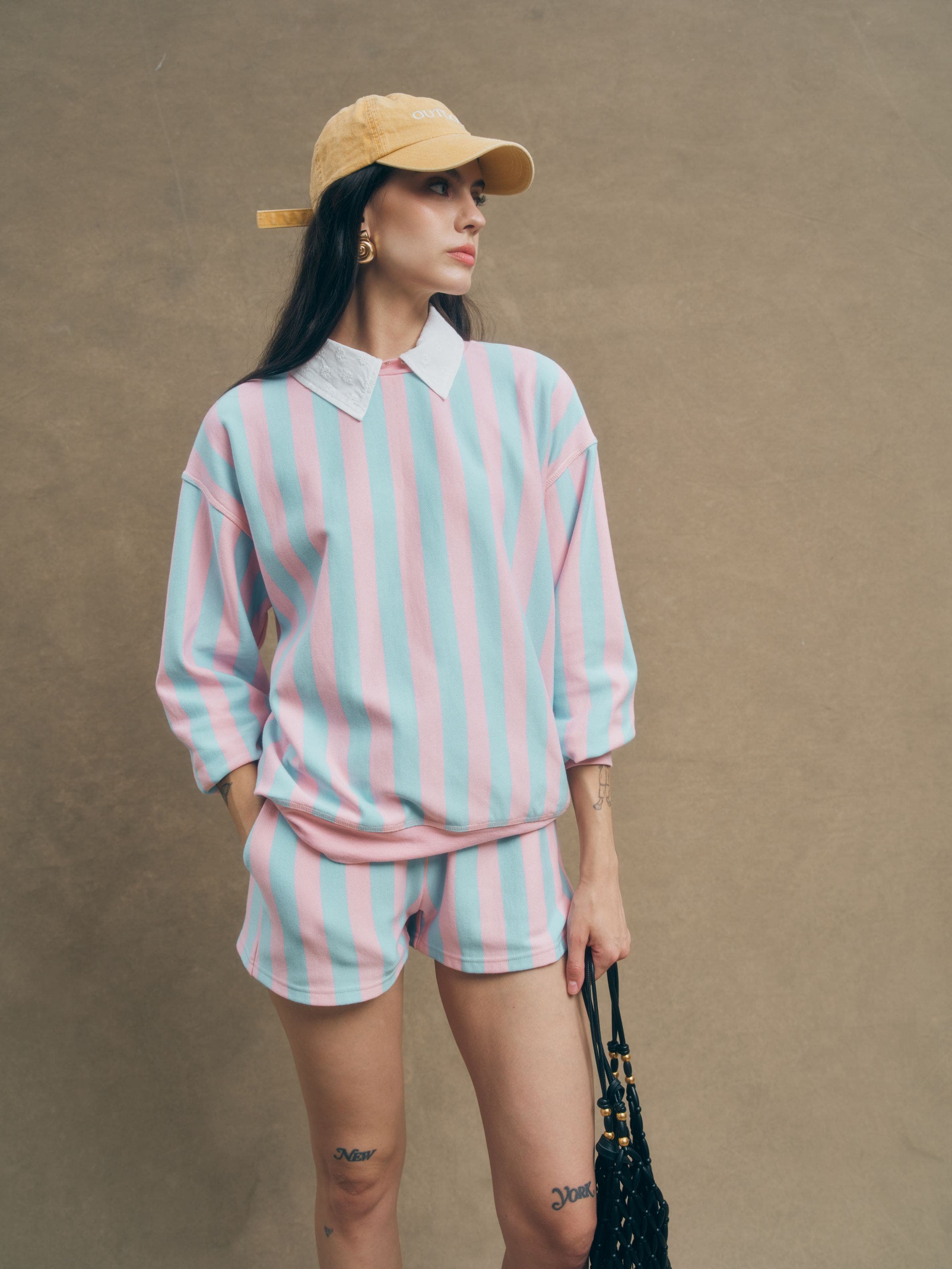 A woman wearing a matching striped sweatshirt and shorts.