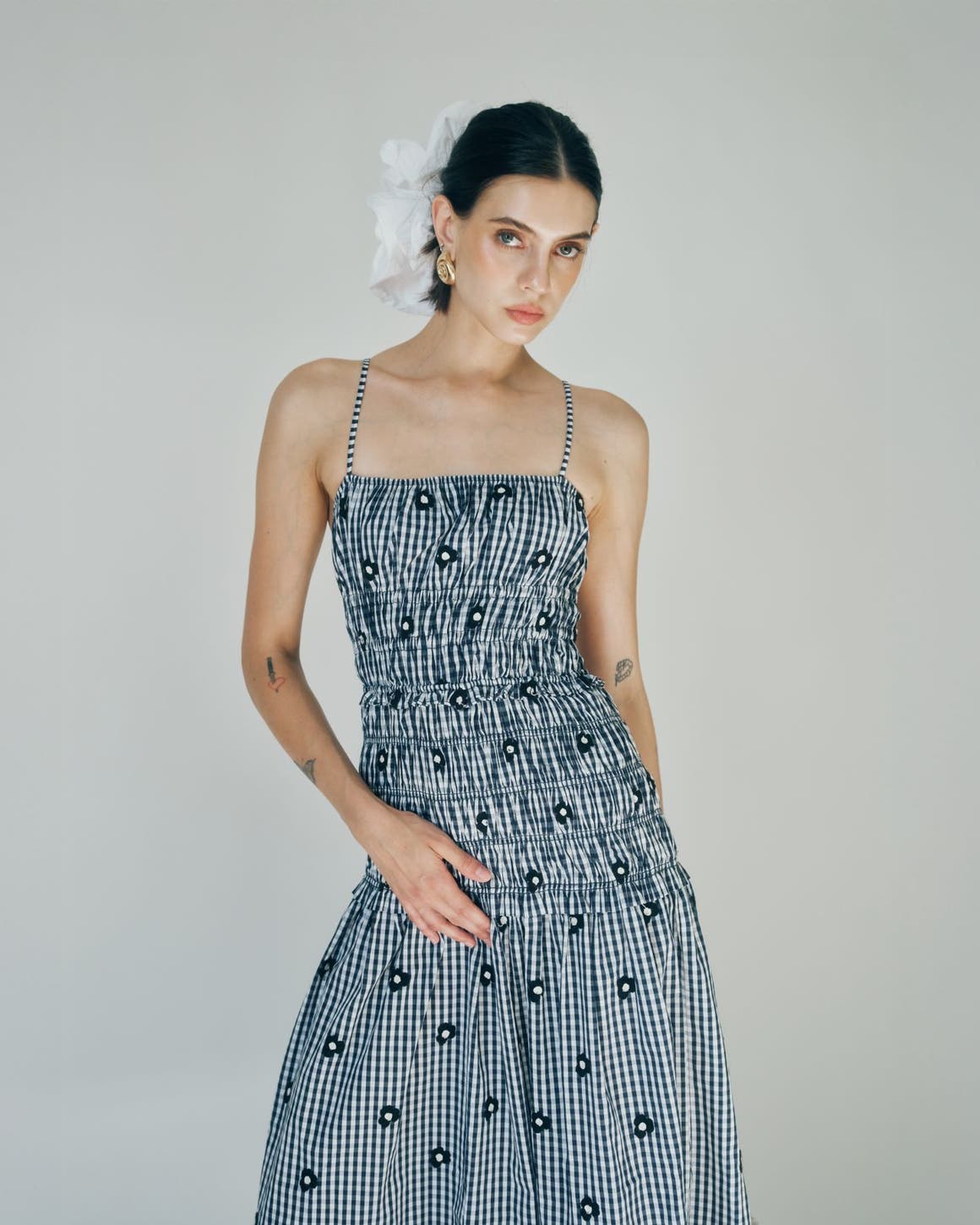 A woman wearing a checked smocked dress with embroidered daisies.